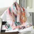 Detail shot of floral printed faux silk scarf draped on white top, elegant lifestyle presentation. - 12
