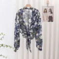 Close-up detail of a blue floral chiffon tie-front shrug cardigan with long sleeves. - Style 1