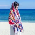 Detailed view of a bohemian style ethnic print cotton linen scarf shawl on beach. - Grey Piano Border Paisley
