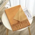 Detailed shot of a cozy double-sided cashmere-feel winter scarf with elegant fringe on a wooden table. - Color 11