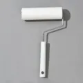 Household lint roller for pet hair removal with sticky paper core and white handle. - White