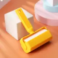 Yellow plastic lint roller for clothes pet hair removal with tearable refill paper core. - Orange