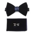 Close-up detail of luxurious velvet men's bow tie, pocket square, and matching metal cufflinks. - Navy Blue