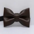 Detailopname van een donkerbruine PU lederen vlinderdas met fijne textuur en strakke afwerking. - koffiekleur