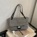 Bolso de hombro de paja a rayas en blanco y negro con correas de cuero y cierre metálico. - Negro