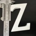 Detail view of the white wooden letter Z being measured with a caliper for size check. - White Letter Z