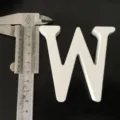 White wooden letter W ornament, detail shot showing precise size with caliper tool for decor. - White Letter W