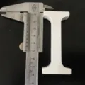 White wooden letter I decorative ornament detail view showing dimensions with caliper tool. - White Letter I