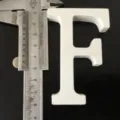 White wooden letter F decor detail view, shown with caliper measuring size for home display. - White Letter F