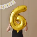 Close-up detail of a shiny gold number 6 foil balloon used for child birthday party decoration. - 32-Inch Gold Number 6 Balloon