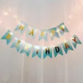Detail view of blue gold Happy Birthday banner with fairy lights for party decoration setup. - Blue Happy Birthday Banner & 2 Warm White Light Strings (Includes Batteries)
