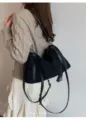 Primer plano del bolso de hombro negro de ante con correas elegantes y un candado. - Negro