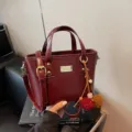 Red faux leather women bucket bag with handle and cute pom-pom pendant for daily wear. - With Pendant / Burgundy