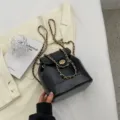Sac à dos seau en cuir noir avec des lanières de chaîne dorées élégantes et fermoir chic. - Noir