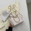 Élégant sac à dos seau en cuir blanc cassé avec bandoulière chaîne dorée et fermoir tourniquet. - Blanc
