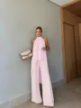 Detailansicht des eleganten rosa Neckholder-Oberteils und der weiten Hose in einem modernen Raum. - XS / Set / Rosa