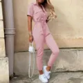Detailaufnahme des rosa Jumpsuits mit Reverskragen, Knopfleiste und Taillengürtel. - S / Rosa