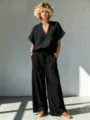 Nahaufnahme Detailansicht des schwarzen Leinen Kurzarm-Oberteils und der weiten Hose. - S / Oberteil und Hose / Schwarz