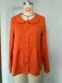 Orange long sleeve blouse featuring peter pan collar, front button closure and peplum waist detail. - As Shown