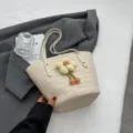 Woven straw bucket shoulder bag for women, summer casual beach tote with cute flower pendant. - Off White