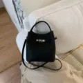 Schwarze Eimerentasche mit Litschimuster, Metall-Drehverschluss und verstellbarem Riemen. - Schwarz ohne Anhänger