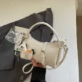 Σικ λευκή τσάντα ώμου ημισέληνος για γυναίκες, κομψή τσάντα PU δέρματος με χαριτωμένο. - Με Μενταγιόν / Ζαχαρί