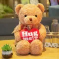 Osito de peluche marrón con cojín de corazón rojo y lazo, suave animal de peluche tierno. - Alga beige con corazón