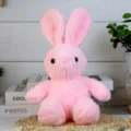 Detail shot of the cute pink plush rabbit toy sitting on a woven mat with cozy room background. - Pink Rabbit / 30cm