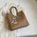 Borsa tote intrecciata in paglia marrone elegante con ciondolo nappa per la spiaggia. - Kaki