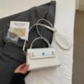 Elegant white patent leather Kelly handbag with top handle and shoulder strap for women. - No Pendant / White