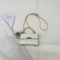 Λευκή λουστρίνι μικρή τετράγωνη τσάντα με μεταλλική κλειδαριά και κομψή λαβή. - Με Μενταγιόν / Λευκό
