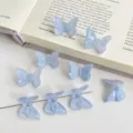 Close-up detail of light blue acrylic butterfly beads with glitter facet design, back hole for DIY hair accessories. - Blue