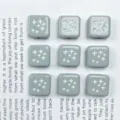 Dettaglio ravvicinato di perline quadrate in acrilico grigio con motivi a stella bianchi in rilievo. - 5# Grigio verniciato