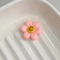 Cute pink resin flower charm with a smiling face, perfect for DIY jewelry and hair accessories. - Honey Pink