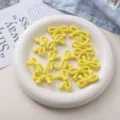 Détail de perles nœud papillon étoile acrylique jaune, parfait pour bijoux DIY et accessoires. - Jaune
