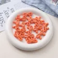 Gros plan détaillé de perles nœud en acrylique orange sur assiette blanche pour bijoux faits main. - Orange Melon