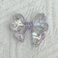 Detailed close-up of a transparent iridescent purple bow acrylic charm for DIY jewelry crafting. - Transparent Purple
