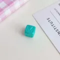 Vista di dettaglio di una perla a cubo in acrilico turchese con lettera M per accessori - Blu lago