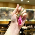 Close-up detail of the pink acrylic conch keychain with gold metal ring and cute bell pendant. - S / Rose Red