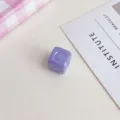 Vista dettagliata di una perla quadrata in acrilico viola pastello con alfabeto inciso in rilievo. - Viola