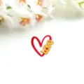 Nahaufnahme eines roten Acryl-Herz-Kuchendeppers mit goldener Aufschrift zum Valentinstag. - Love (Feste Rote Basis + Goldene Oberfläche)