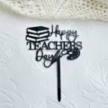 Detailansicht des schwarzen Acryl Torte Toppers Happy Teachers Day mit Büchern und Farbpalette. - Alles Gute zum Lehrertag / Schwarz
