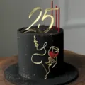 Close-up of minimalist black cake with gold acrylic 25 topper and artistic face line decoration. - Glitter Wine Glass Woman (No 25) / Gold