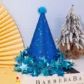 Dettaglio cappello festa blu glitterato, con stelle lucide e pompon per feste di compleanno. - Cappello di compleanno blu scuro