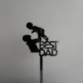 Detail view of black acrylic Best Dad cake topper for Father's Day party decor. - Best Dad Lifting Child Design / Width Approx 8CM / Black