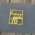 Detailed view of the yellow acrylic 70th birthday cake topper with cutout text design. - Number 70 Happy Birthday Mirror Gold / 1.3mm Thick (Width Approx 10cm)