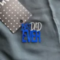 Detailed close-up of blue and silver acrylic Best Dad Ever cake topper on dark textured fabric. - Royal Blue & Silver - Best Dad (Side Ornament) / Width Approx 7CM