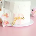 Nahaufnahme des rosa-goldenen Acryl Kuchenaufsteckers mit Liebe Aufschrift auf Torte. - Love You (Rosa Basis + Goldene Oberfläche)