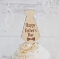 Close-up detail of wooden Father's Day tie cake topper featuring engraved greeting text element. - Tie Shape / Width Approx 5CM