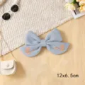 Close-up detail of light blue fabric bow hair clip featuring delicate swan embroidery. - Swan Ribbon Knot / Blue